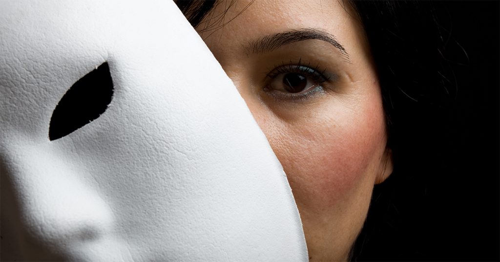 Woman peeking from behind white drama mask